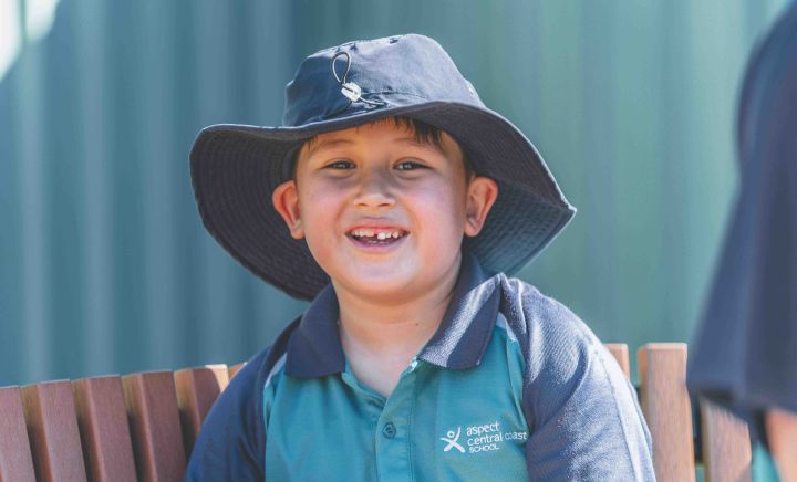 Student smiling outdoors wearing school hat